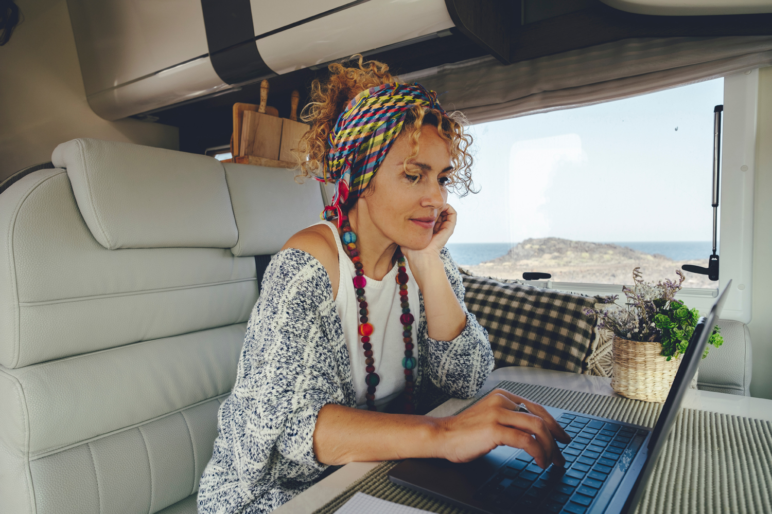 Attracive young adult woman using laptop computer inside camper